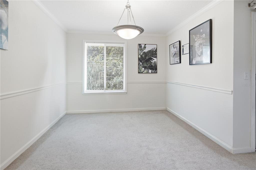A dining room with white walls, chair rail molding, carpeted flooring, and a central pendant light — 8880 OLD KINGS ROAD S UNIT 4, JACKSONVILLE, FL