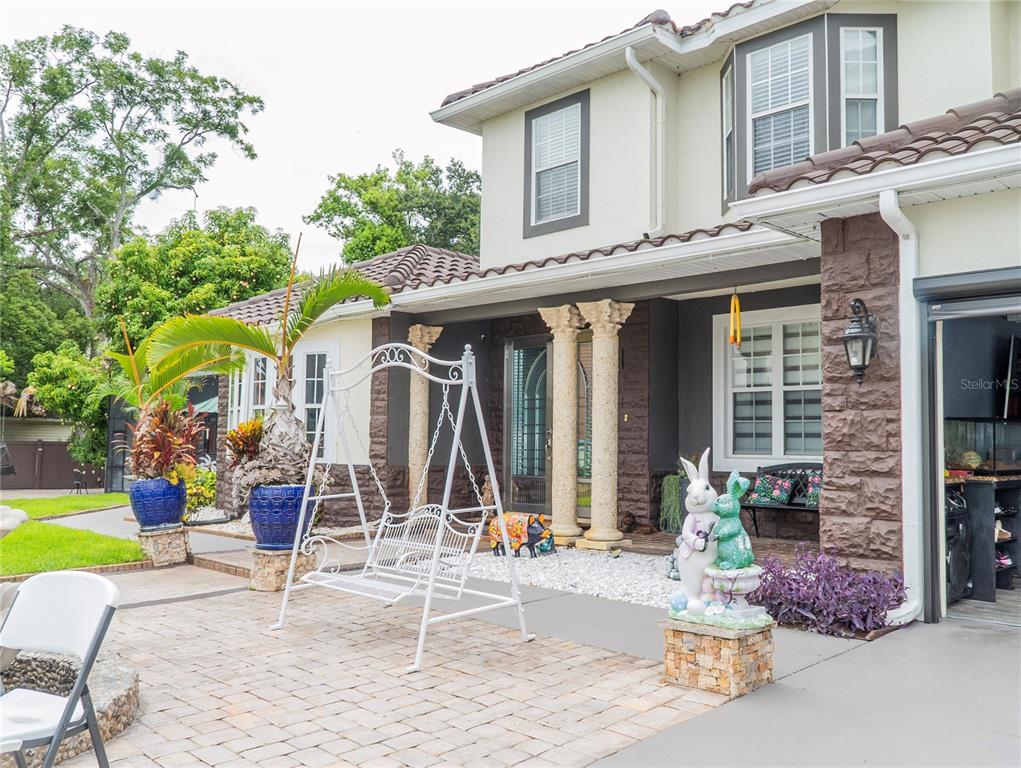 A two-story house exterior features a stone-accented facade, decorative columns, and a paved patio area — 1304 OCOEE APOPKA ROAD, OCOEE, FL