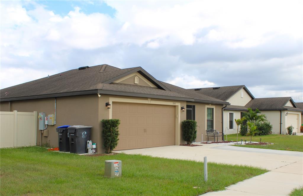 A tan single-story house with a two-car garage and a brown shingled roof — 1552 SWAN LAKE CIRCLE, DUNDEE, FL