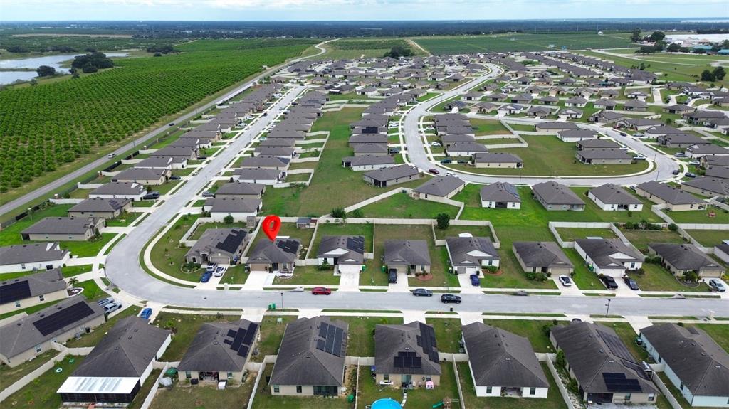 An aerial view shows a suburban neighborhood with many houses featuring rooftop solar panels — 1552 SWAN LAKE CIRCLE, DUNDEE, FL