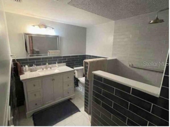 A bathroom features a gray vanity, dark subway tile walls, and a walk-in shower — 751 ARABIAN CIRCLE, NOKOMIS, FL