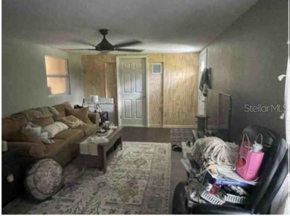 A living room features a brown sofa, a patterned area rug, and plywood wall paneling — 751 ARABIAN CIRCLE, NOKOMIS, FL