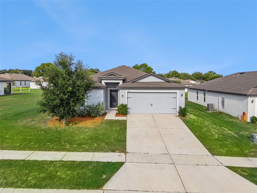 A single-story suburban house with a gray exterior, a two-car garage, and a concrete driveway — 1350 BRENWAY DRIVE, MASCOTTE, FL