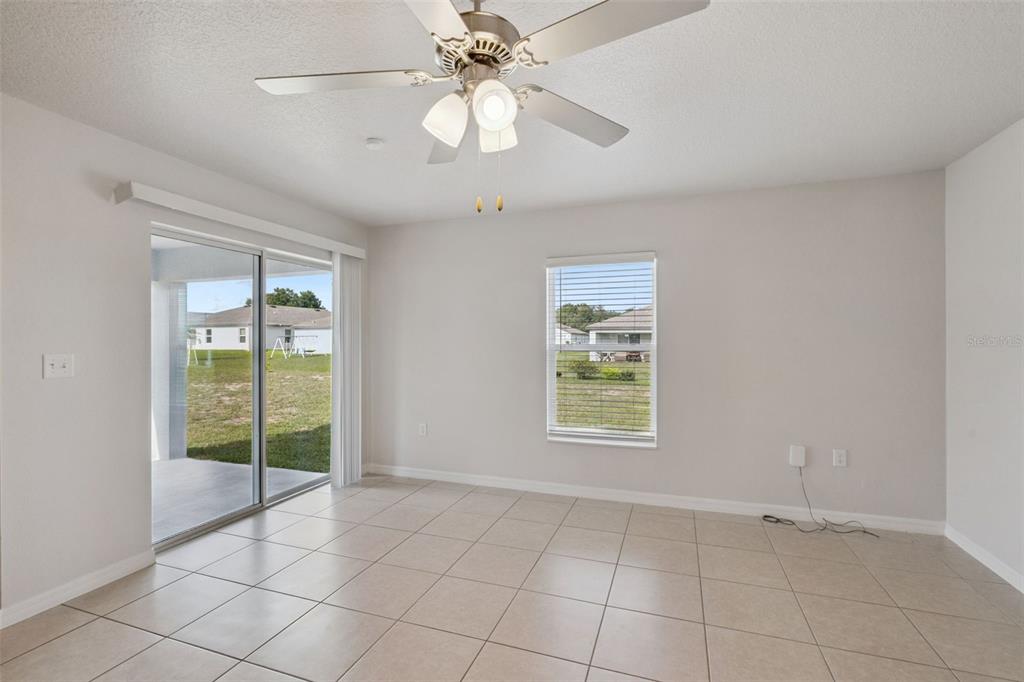 A bright room with light tile flooring, a ceiling fan, and a sliding glass door — 1350 BRENWAY DRIVE, MASCOTTE, FL