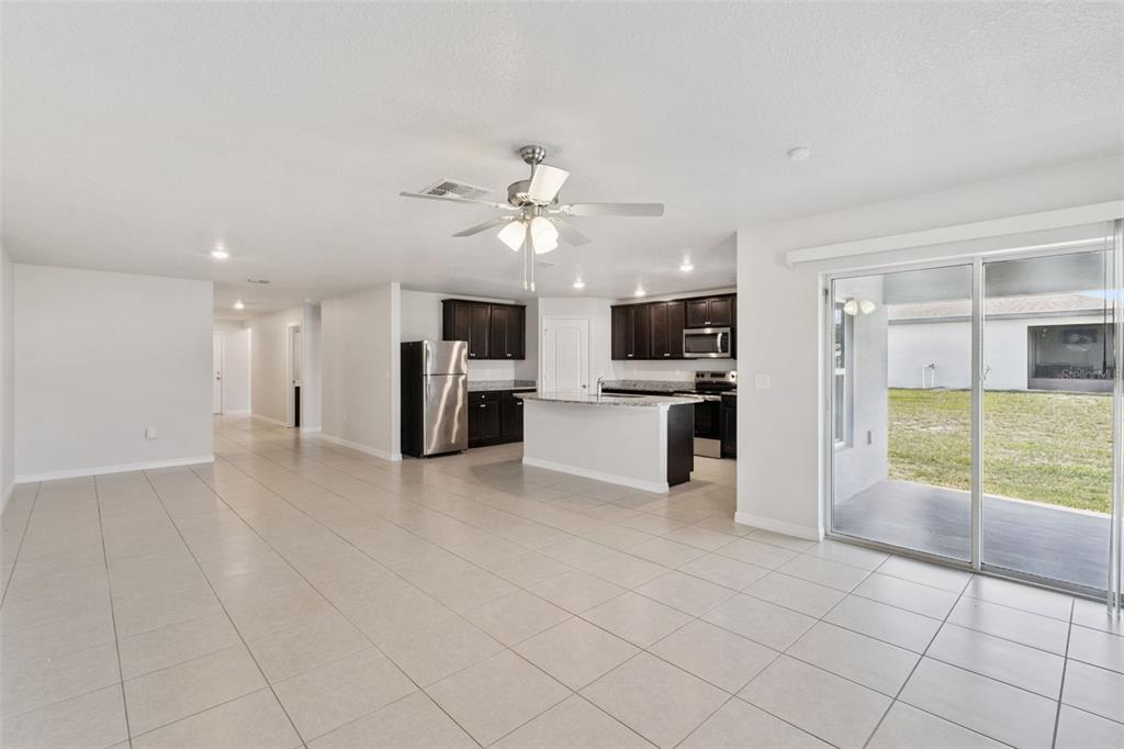 An open-concept kitchen and living area with tile floors, dark cabinetry, and a sliding door — 1350 BRENWAY DRIVE, MASCOTTE, FL