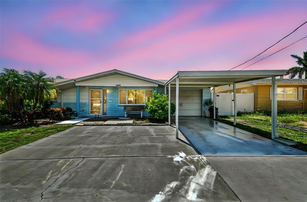 A single-story house with a blue exterior, a concrete driveway, and an attached metal carport — 13603 ALLYN DRIVE, HUDSON, FL
