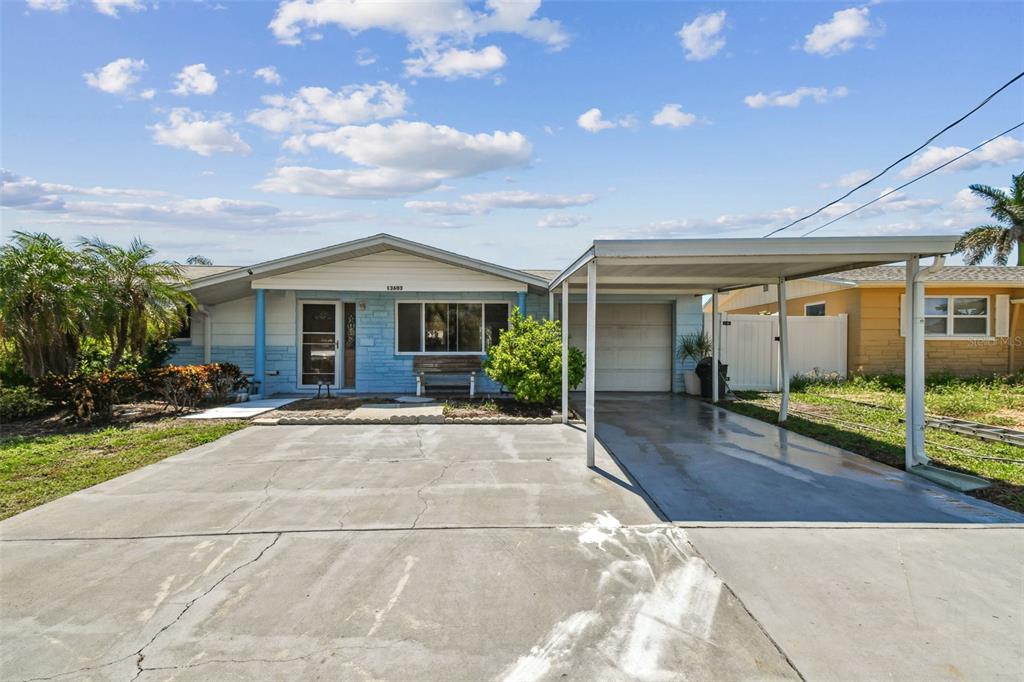 A single-story house with a light blue facade, a concrete driveway, and an attached carport — 13603 ALLYN DRIVE, HUDSON, FL