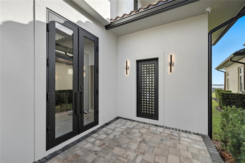 A paved patio area features a set of glass double doors and a single decorative door — 16142 TRIVOLI CIRCLE, MONTVERDE, FL