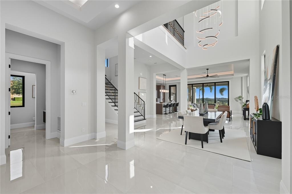 A bright, open-concept dining area features high ceilings, a modern chandelier, and polished tile floors — 16142 TRIVOLI CIRCLE, MONTVERDE, FL
