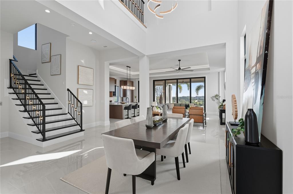 A dining area with a dark wood table and white chairs sits before an open living space — 16142 TRIVOLI CIRCLE, MONTVERDE, FL