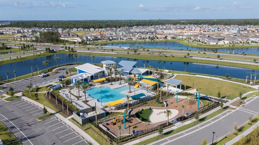 An aerial view shows a community swimming pool, playground, and clubhouse surrounded by residential homes — 13463 GOOD VIBES AVENUE, ORLANDO, FL