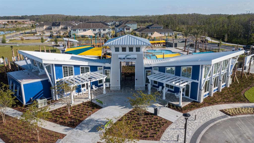 An aerial view of a blue community clubhouse with a pool and playground in the background — 13463 GOOD VIBES AVENUE, ORLANDO, FL