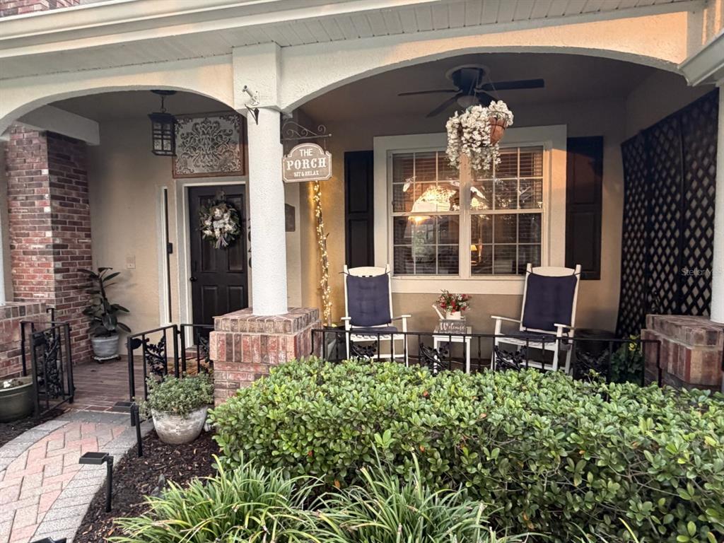 A covered front porch features two rocking chairs, a hanging plant, and brick columns — 2040 PARK FOREST BOULEVARD, MOUNT DORA, FL