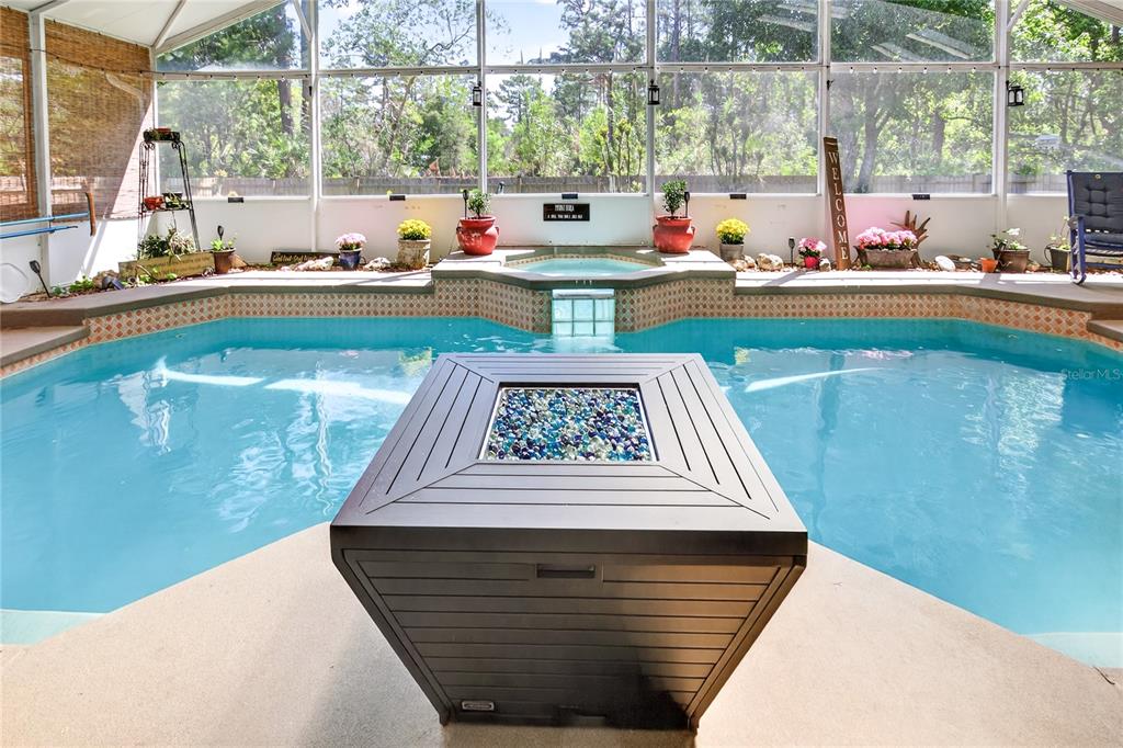 A screened-in pool area features a fire pit table, a raised spa, and potted plants — 2040 PARK FOREST BOULEVARD, MOUNT DORA, FL