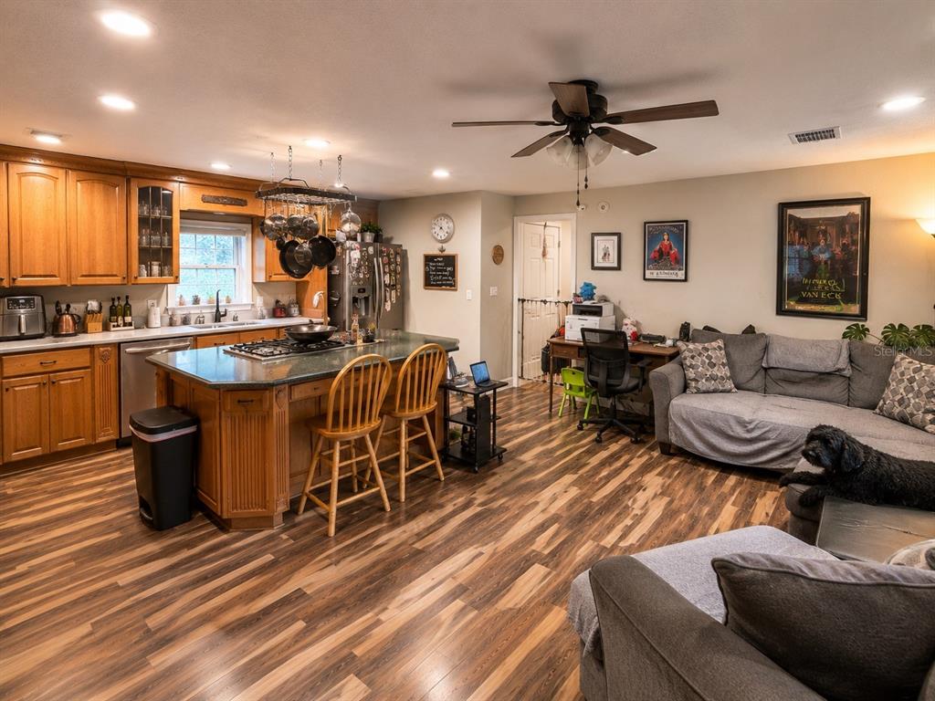 An open-concept kitchen and living area features wood cabinetry, a central island, and wood flooring — 9390 NE 16TH TERRACE, ANTHONY, FL