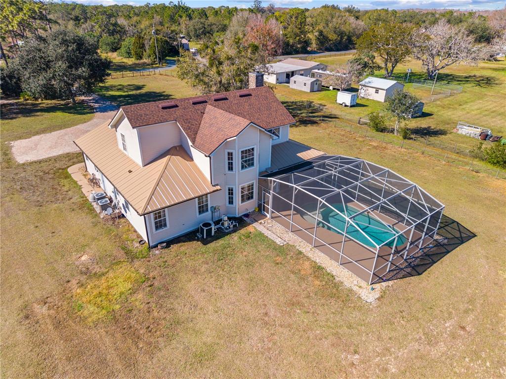 An aerial view of a two-story house with a metal roof and a screened-in pool — 3255 TUCKER AVENUE, ST CLOUD, FL