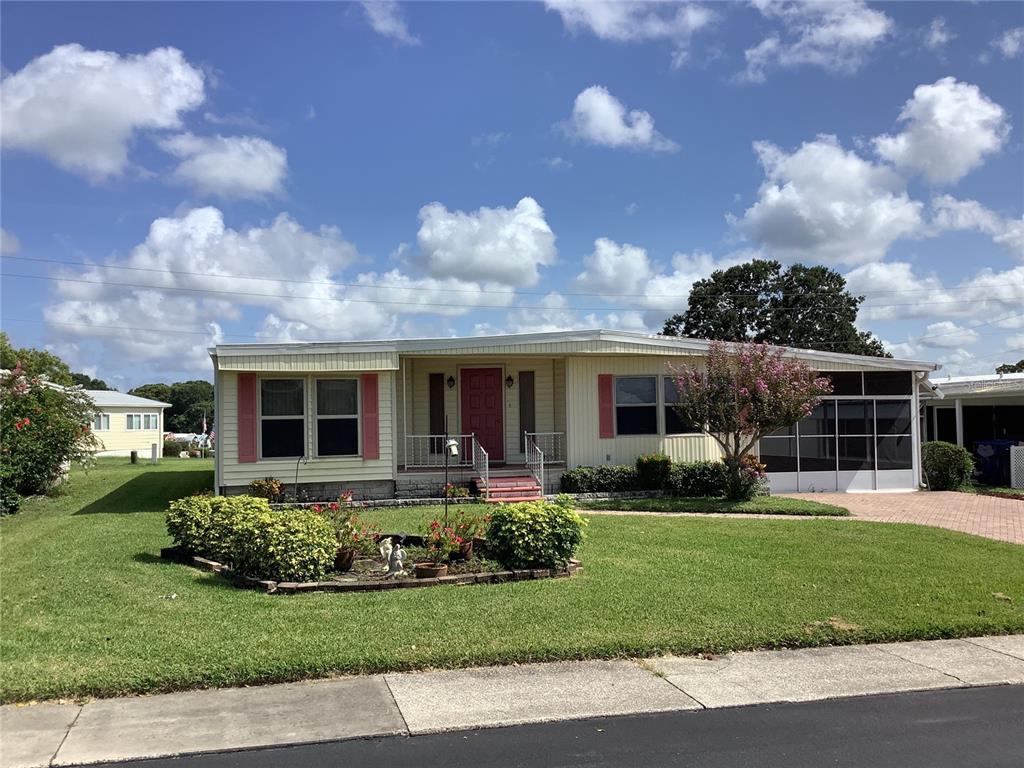 A single-story manufactured home features yellow siding, a red front door, and a landscaped yard — 269 SALEM AVENUE UNIT 9, PALM HARBOR, FL