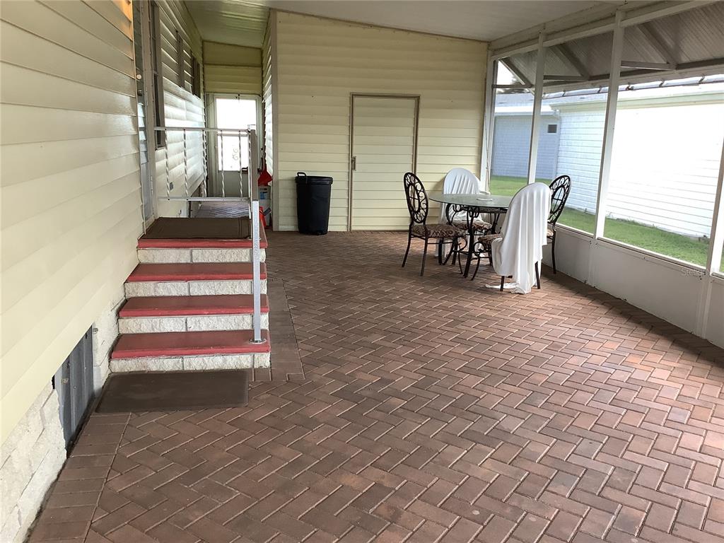 A covered patio features red brick pavers, a set of steps, and outdoor furniture — 269 SALEM AVENUE UNIT 9, PALM HARBOR, FL