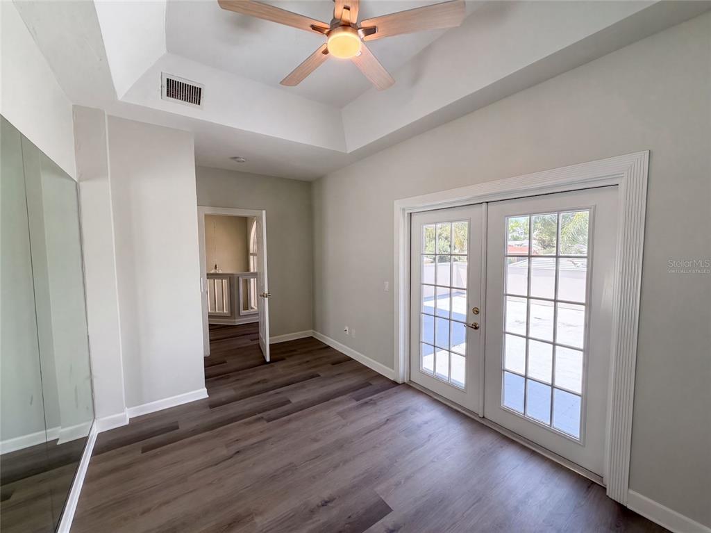 A room with wood-look flooring, a tray ceiling with a fan, and French doors leading outside — 24 BAY POINTE DRIVE, ORMOND BEACH, FL