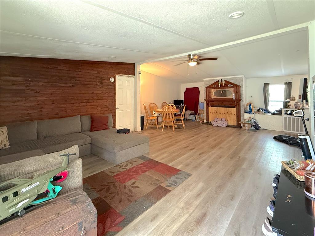 A living room with wood-paneled walls, light wood flooring, and an adjacent dining area — 42135 PINE VALLEY DRIVE, PAISLEY, FL