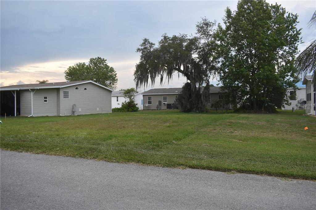 A grassy vacant lot sits between two residential houses under a cloudy sky — LOT 45 BLK C LEXINGTON- CIRCLE, WILDWOOD, FL