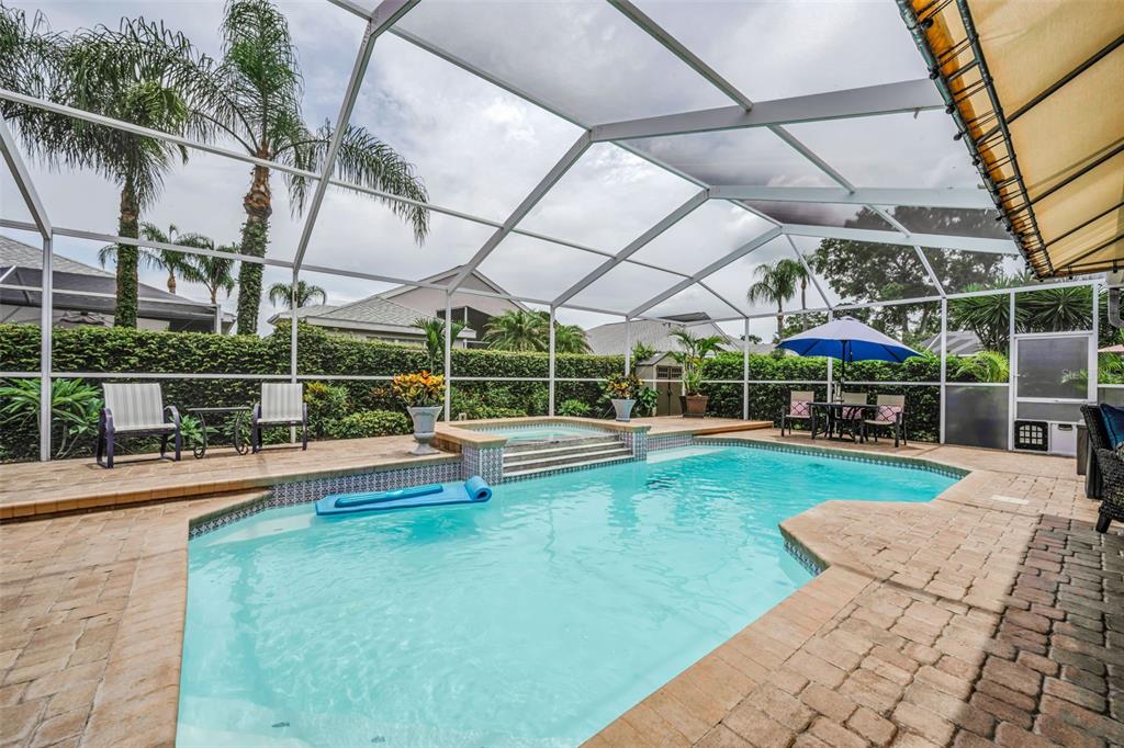 A screened-in swimming pool and hot tub with a paver deck and patio furniture — 1114 TOSKI DRIVE, TRINITY, FL