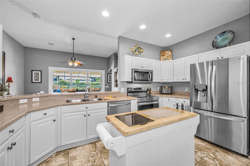 A kitchen with white cabinets, stainless steel appliances, a wooden island, and tile flooring — 1114 TOSKI DRIVE, TRINITY, FL