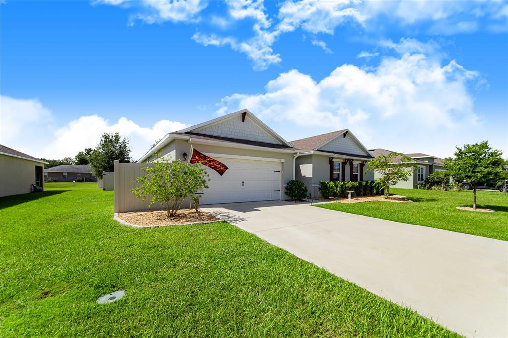 A single-story suburban house with a two-car garage, a concrete driveway, and a grassy lawn — 803 AUBURN GROVE COURT, AUBURNDALE, FL