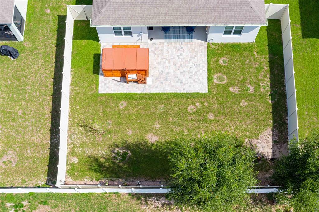 An aerial view shows a fenced backyard with a patio, hot tub, and large tree — 803 AUBURN GROVE COURT, AUBURNDALE, FL