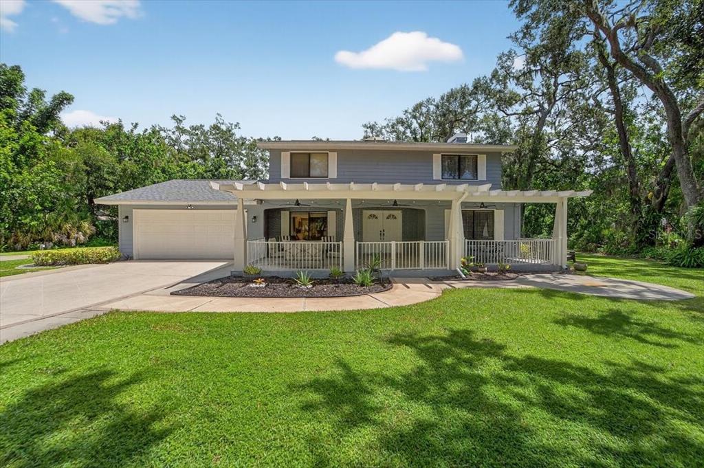 A two-story house with a white pergola-covered porch, a two-car garage, and a front lawn — 6512 93RD STREET E, BRADENTON, FL