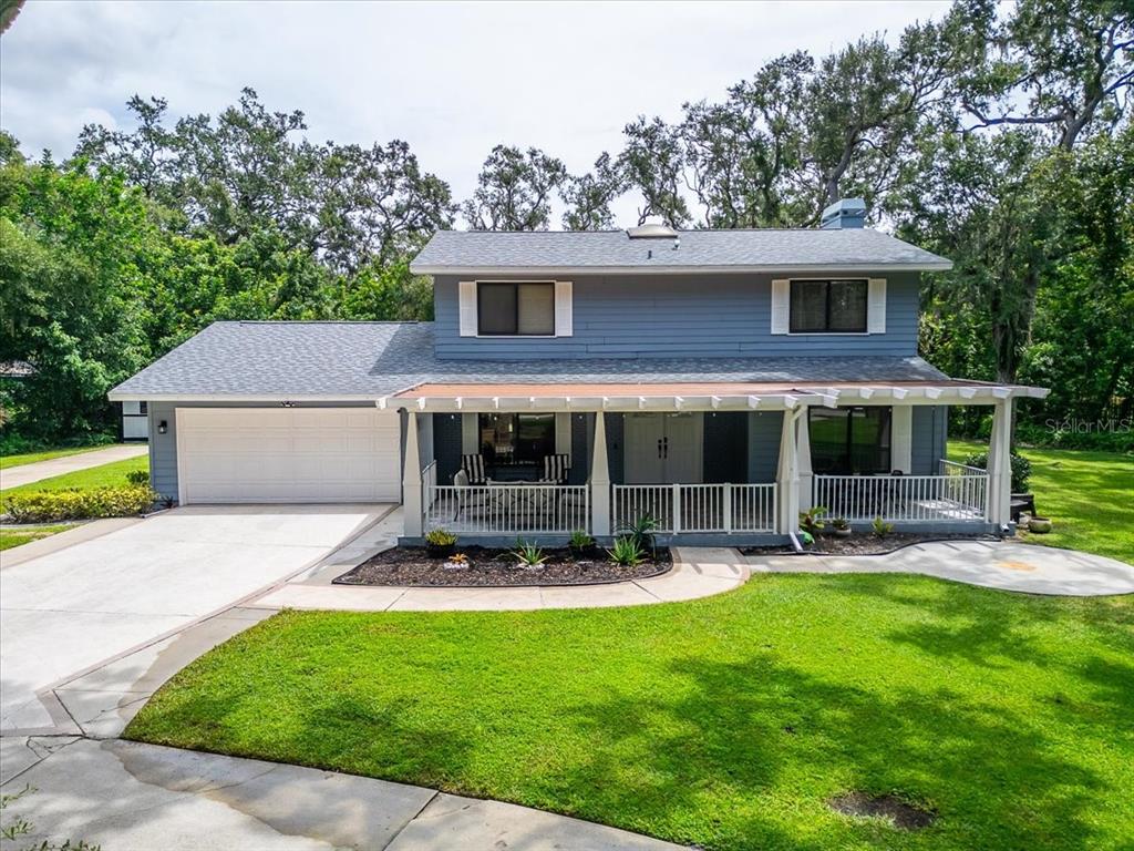 A two-story blue house with a white garage, a covered front porch, and a lawn — 6512 93RD STREET E, BRADENTON, FL