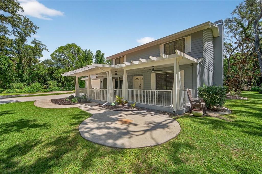 A two-story house with a white pergola-covered patio and a concrete walkway on a lawn — 6512 93RD STREET E, BRADENTON, FL