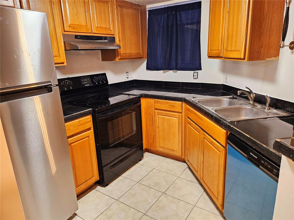A kitchen with wood cabinets, stainless steel appliances, and a breakfast bar — 1916 LAKE ATRIUMS CIRCLE UNIT 25, ORLANDO, FL
