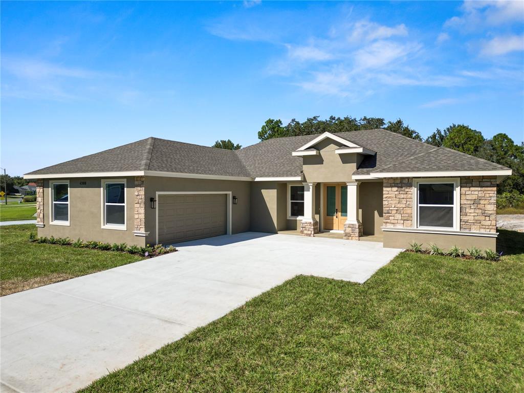 A single-story house exterior features a concrete driveway, stone accents, and a double front door — 4300 CREMONA DRIVE, SEBRING, FL