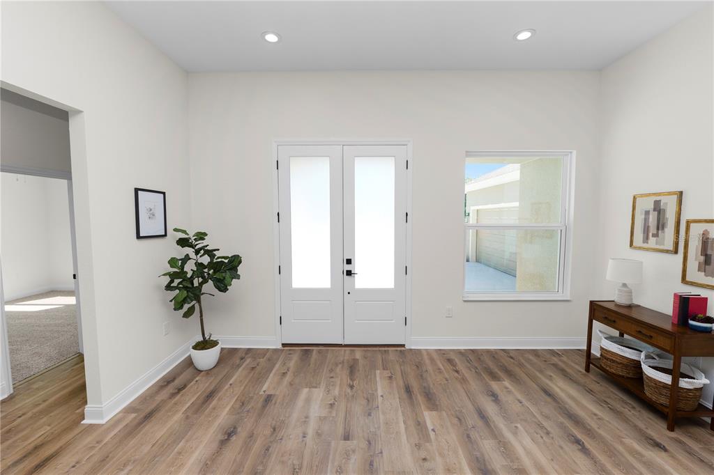 A bright entryway features double glass-paneled doors, wood-look flooring, and a small console table — 4300 CREMONA DRIVE, SEBRING, FL