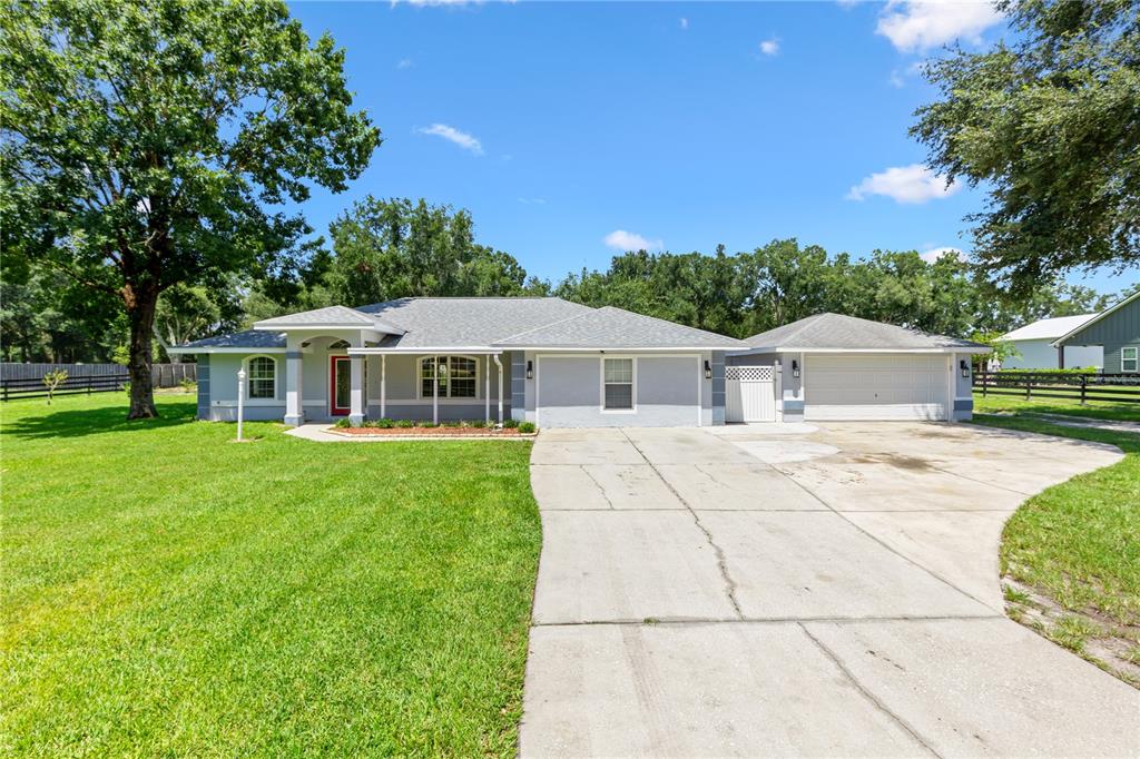 A single-story house with a gray exterior, a red front door, and an attached garage — 2607 SE 156TH PLACE ROAD, SUMMERFIELD, FL