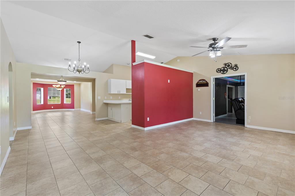 An open-concept living area features tile flooring, a red accent wall, and a ceiling fan — 2607 SE 156TH PLACE ROAD, SUMMERFIELD, FL