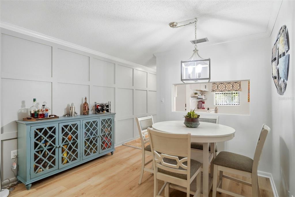 A dining room features a blue sideboard, a round table with chairs, and wall molding — 2700 NEBRASKA AVENUE UNIT 2-203, PALM HARBOR, FL