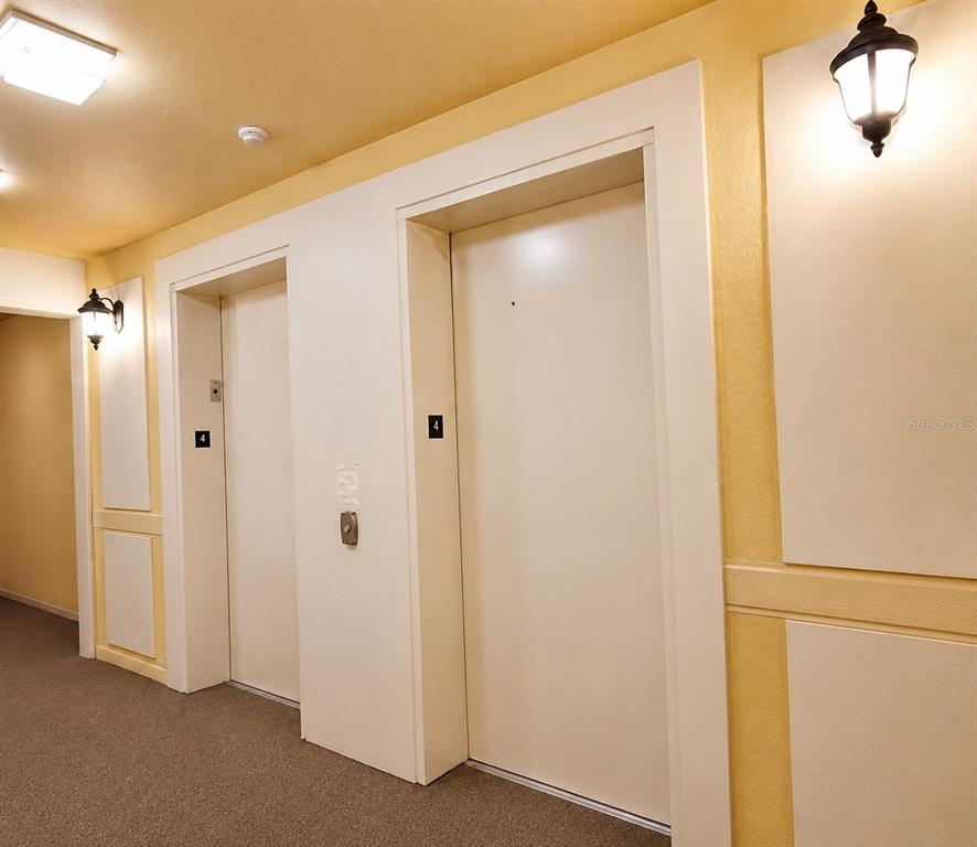 A hallway features two elevator doors marked with the number four and wall-mounted light fixtures — 3338 ROBERT TRENT JONES DRIVE UNIT 410, ORLANDO, FL