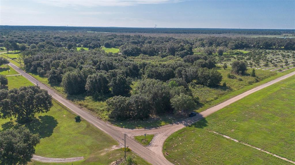An aerial view shows a dirt road intersection bordering a wooded lot and open fields — YALE HAMMOCK ROAD, UMATILLA, FL