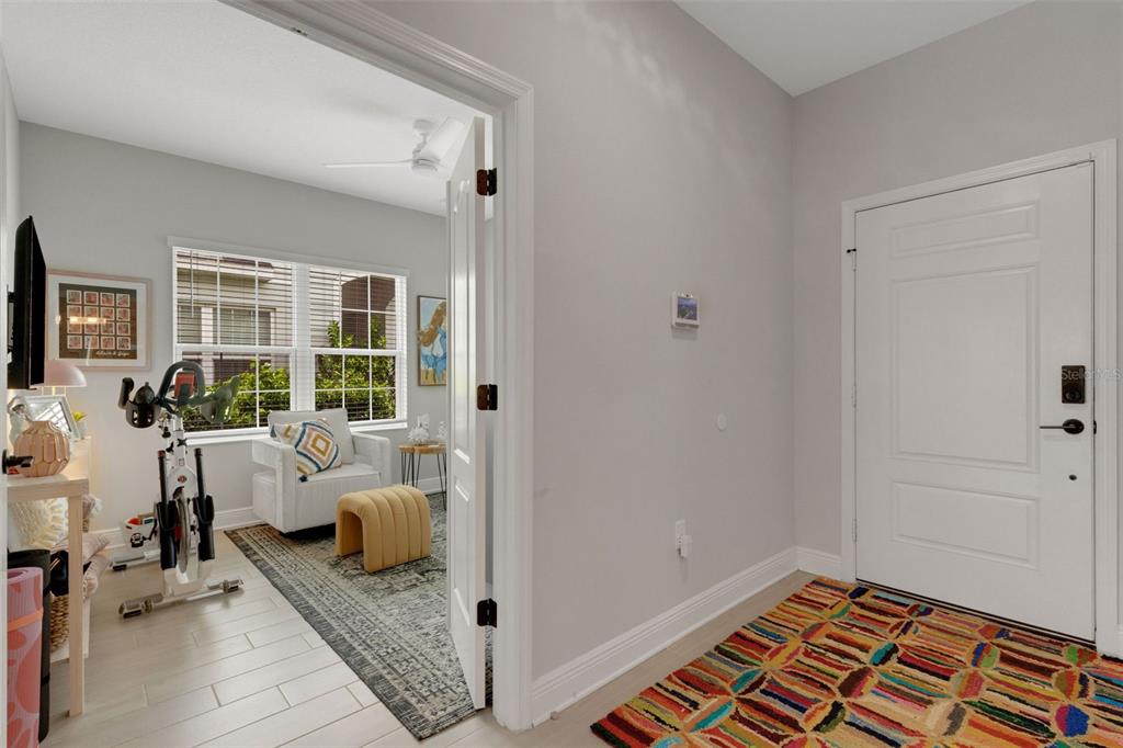 An entryway with a colorful rug leads into a room containing an exercise bike — 4661 WILLOW BEND AVENUE, PARRISH, FL