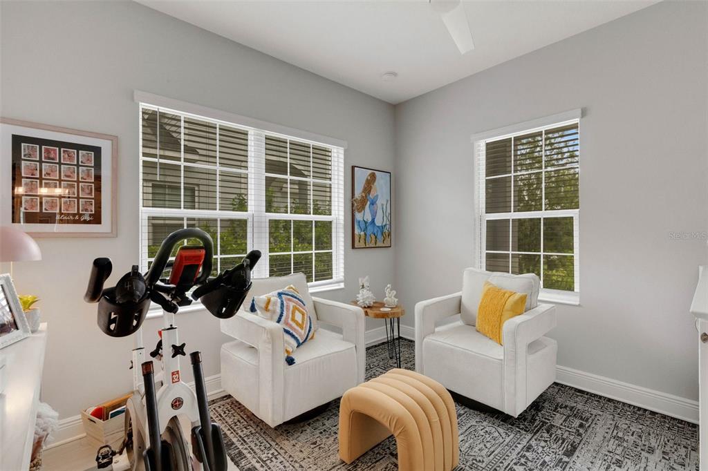 A room with two white armchairs, a yellow ottoman, and an exercise bike on a rug — 4661 WILLOW BEND AVENUE, PARRISH, FL