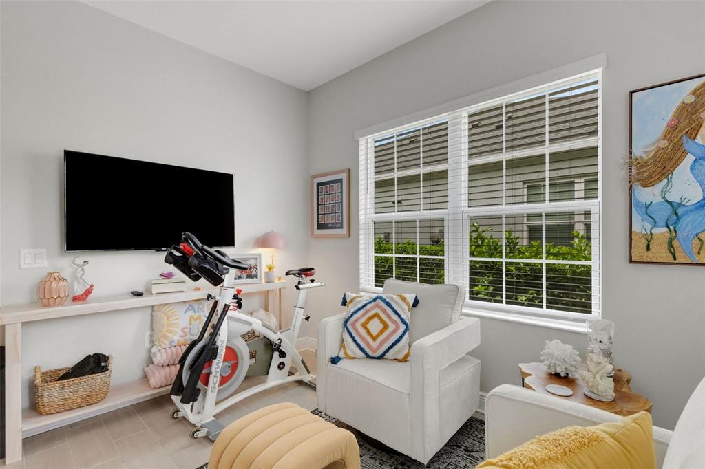 A room features a stationary bike, a white armchair, a television, and a window — 4661 WILLOW BEND AVENUE, PARRISH, FL