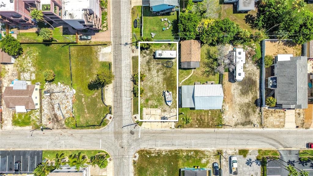 An aerial view shows a rectangular vacant lot with a trailer and boat parked on it — 14065 PALM ST, MADEIRA BEACH, FL
