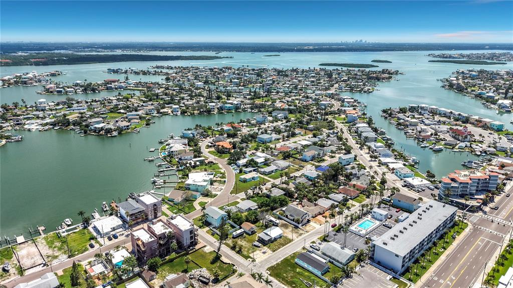 An aerial view shows a coastal neighborhood with houses, canals, and a large apartment building — 14065 PALM ST, MADEIRA BEACH, FL
