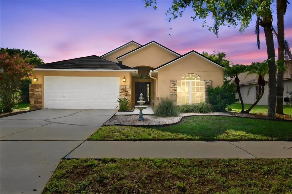A single-story house with a tan stucco exterior, a two-car garage, and a front fountain — 6637 THACKSTON DRIVE, RIVERVIEW, FL