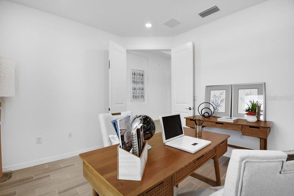A home office features a wooden desk, a white laptop, and double doors — 5780 BINNACLE LANE, COCOA, FL