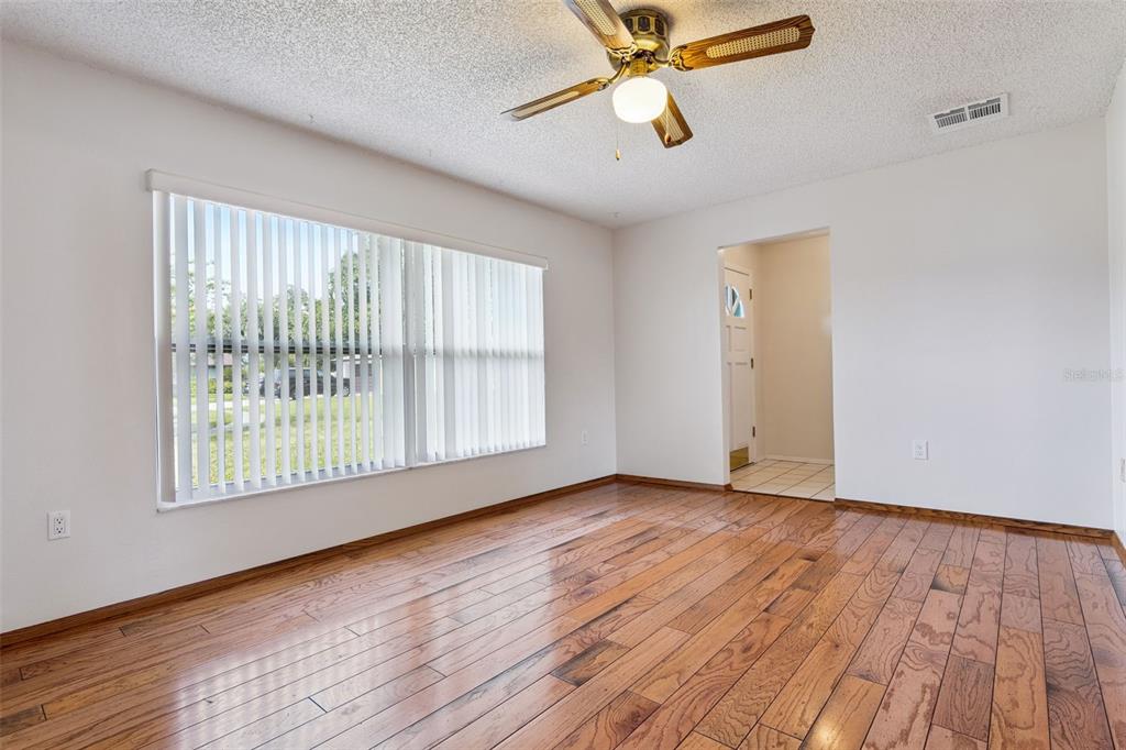 A living room with hardwood floors opens to a kitchen with wood cabinets and tile flooring — 4101 PLAYA COURT, BELLE ISLE, FL