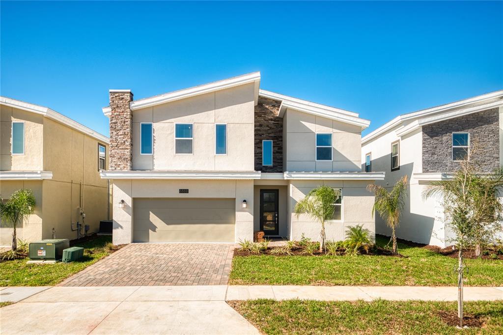 A two-story house with a stone-accented facade, a two-car garage, and a paved driveway — 8888 CABOT CLIFFS DRIVE, DAVENPORT, FL