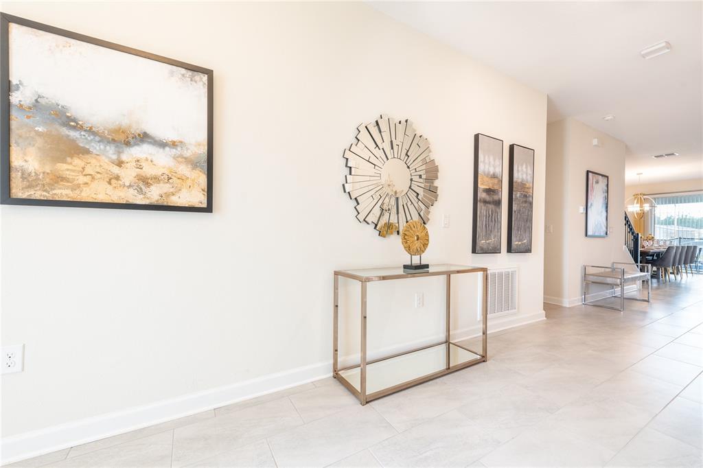 A bright entryway features light tile flooring, a glass console table, and wall art — 8888 CABOT CLIFFS DRIVE, DAVENPORT, FL